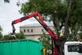 Worker with a crane on truck removing tree branches after cutting at the urban park in the street