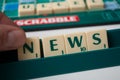 Closeup of plastic letters with word news in hand on Scrabble board game Royalty Free Stock Photo