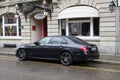 Profile view of black Mercedes e400 d parked in the street by rainy day