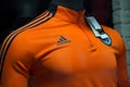 Orange teeshirt of soccer by adidas brand in a fashion store showroom