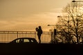Silhouette of woman taking a photography on bridge with smartphone in hands by sunset Royalty Free Stock Photo