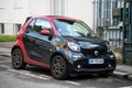Front view of black and red smart microcar parked in the street