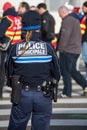 Portrait on back view of municipal police woman looking protesting people walking in the street