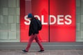 Portrait of man walking in the street in front of fashion store with text in french `SOLDES` traduction in english Sales Royalty Free Stock Photo