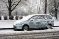 Profile view of blue Peugeot 807 monospace covered by the sow parked in the street by snowy day