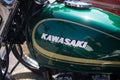 Closeup of Kawazaki logo on green tank of Kawazaki motorbike parked in the street