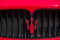 Closeup of Maserati logo on red sport car parked in the street