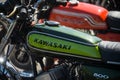 Kawazaki logo on green tank of vintage motorbike parked in the street