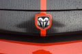 Closeup of rain drops of Dodge challenger logo on orange and black car parked in the street