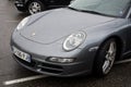 Front view of grey Porsche 911 parked in the street by rainy day