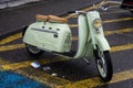 Profile view of green vintage scooter parked in the street by rainy day