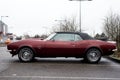 Profile view of red camaro car parked in the street by rainy day