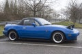 Profile view of vintage Mazda MX5 parked in the street by rainy day