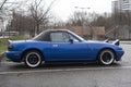 Profile view of vintage Mazda MX5 parked in the street by rainy day