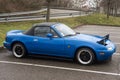 Profile view of vintage Mazda MX5 parked in the street by rainy day