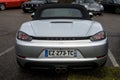 Rear view of grey Porsche 718 parked in the street by rainy day