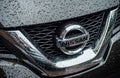 Closeup of rain drops on Nissan logo on black 4X4 car front
