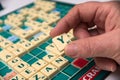 Hand of woman playing with plastic letter Y to forming a word on Scrabble board game