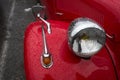 Closeup of rain drops on headlight of red Citroen traction parked in the street
