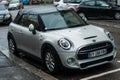 Front view of white mini cooper s parked in the street by rainy day