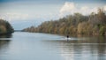 One man with boat rowing training on the river in autumn
