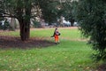 Portrait of municipal employee working in a public garden to blowing leaves