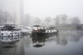 Boats in the harbor on the river by foggy day on trees silhouettes background