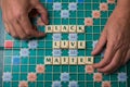 Hands of man forming the word `Black Live Matter` with scrabble letters on the game board