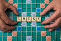 Hands of man forming the word Lucky with scrabble letters on the game board