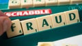 Plastic letters on Scrabble board game forming the word : Fraud Royalty Free Stock Photo