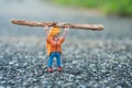 Playmobil figurine carrying a tree trunk above the head on the road