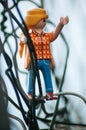 Playmobil figurine climbing on metallic fence in outdoor