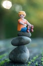 Playmobil figurine sitting on stone balance in outdoor