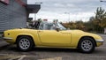 Profile view of Yellow vintage Lotus Elan roadster parked in the street