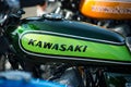 Kawazaki logo on green tank of vintage motorbike parked in the street