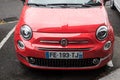 Front view of corail color Fiat 500 parked in the street by rainy day