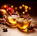 Mulled cider with slice apples, cinnamon, cloves, anise stars and citrus fruits in glass cups on a wooden rustic table, close-up. Royalty Free Stock Photo