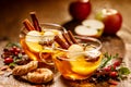 Mulled cider with slice apples, cinnamon, cloves, anise stars and citrus fruits in glass cups on a wooden rustic table, close-up. Royalty Free Stock Photo