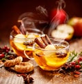 Mulled cider with slice apples, cinnamon, cloves, anise stars and citrus fruits in glass cups on a wooden rustic table, close-up. Royalty Free Stock Photo