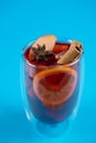 Mulled wine on blue background. Alcohol punch in double glass cup. Drink with orange, anise star, cinnamon and apple. Royalty Free Stock Photo