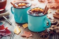 Mulled wine in blue enameled mugs with spices and citrus fruit on table with autumn leaves. Royalty Free Stock Photo