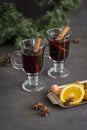 Mulled wine in glasses at black background. Fir wreath, tray with orange, cinnamon, nuts, cone and spices near Royalty Free Stock Photo