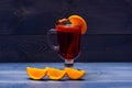 Mulled wine with orange juice. Drink and cocktail concept. Glass with mulled wine near juicy orange fruit on dark blue Royalty Free Stock Photo