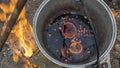 Mulled wine in a tourist pot over hot camp fire. Mulled wine by the fire. Mulled wine cooked on fire outdoors. Picnic. Royalty Free Stock Photo