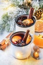 Mulled wine in white metal mugs with cinnamon, spices and orange with fir tree and christmas lights - traditional drink on winter Royalty Free Stock Photo