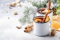 Mulled wine in white metal mugs with cinnamon, spices and orange with fir tree and christmas lights - traditional drink on winter Royalty Free Stock Photo