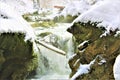 Mullerthal, Luxembourg - January 2024, winter - A small river with frozen water in the forest under snow Royalty Free Stock Photo