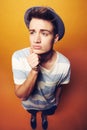 Mulling things over. Studio shot of a young man in a hat with a puzzled facial expresison. Royalty Free Stock Photo