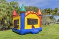 A multi-color castle bounce house photographed from the left side