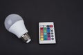 Multi color led bulb with a remote control on a black background Royalty Free Stock Photo